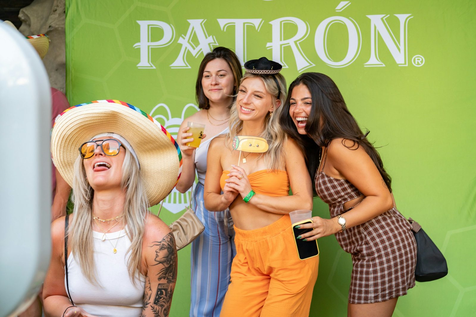 Guests laughing together with props in front of an event backdrop